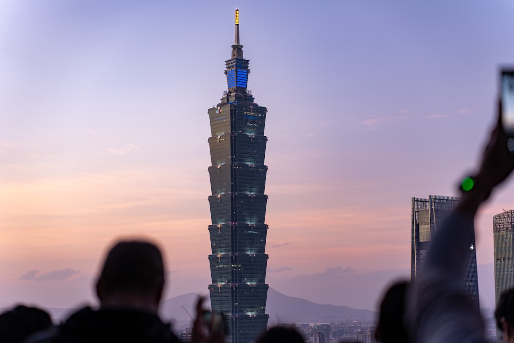 a group of people taking pictures of a tall building