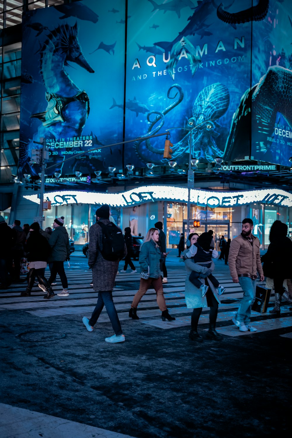 a group of people walking across a street at night