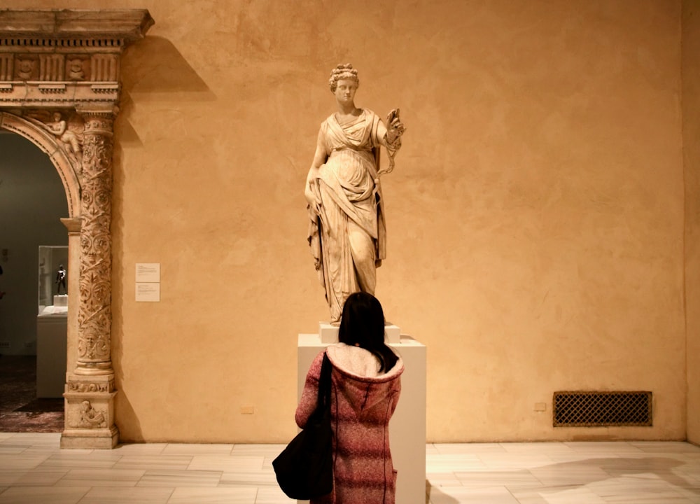 eine Frau, die eine Statue in einem Museum betrachtet