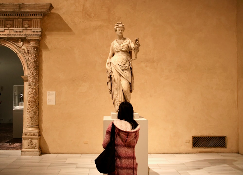 a woman looking at a statue in a museum