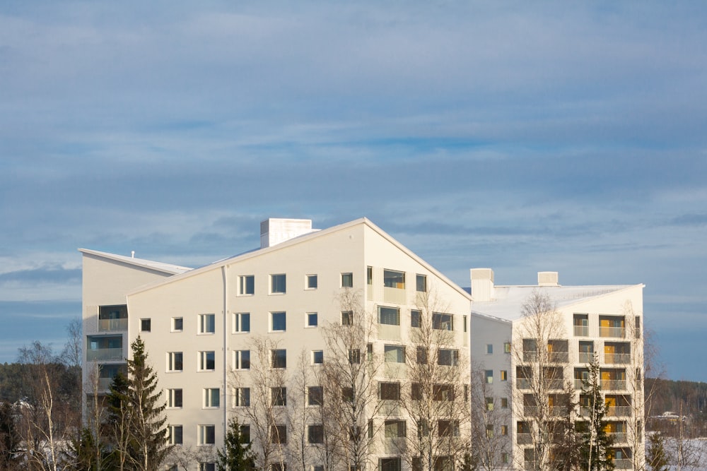 a large white building sitting next to a forest