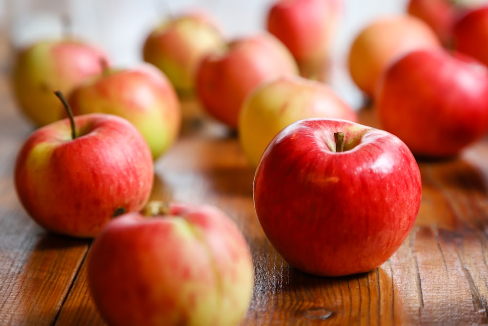 un gruppo di mele rosse seduto sopra un tavolo di legno