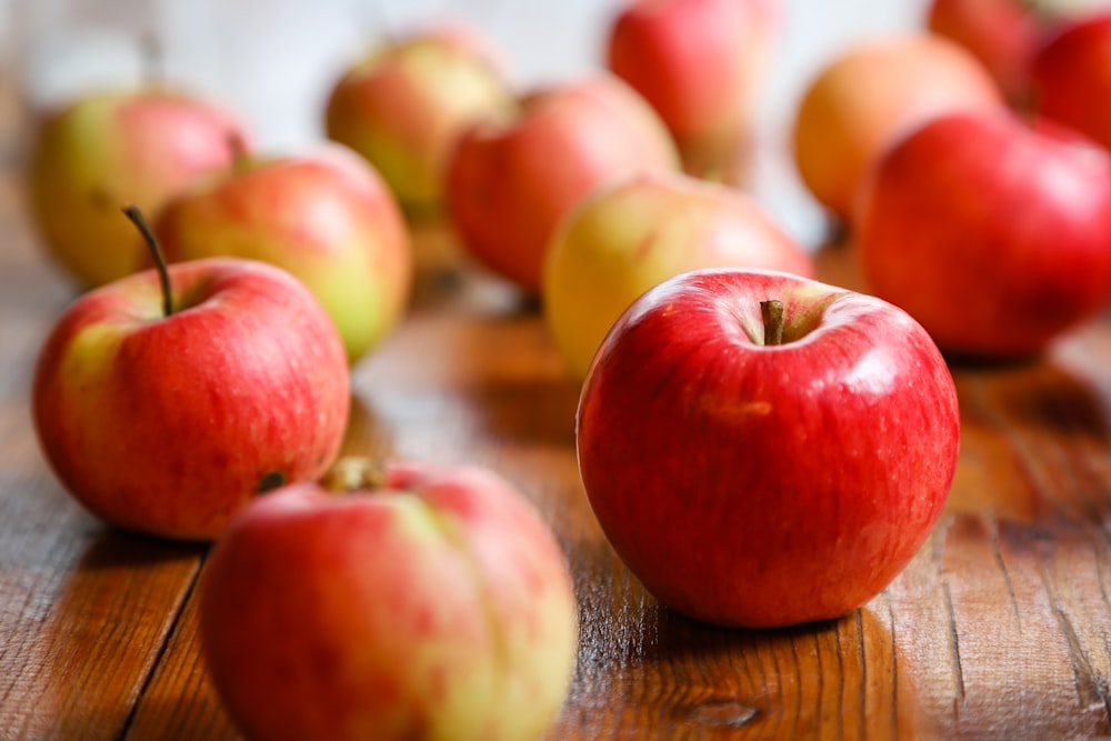 a group of red apples sitting on top of a wooden table