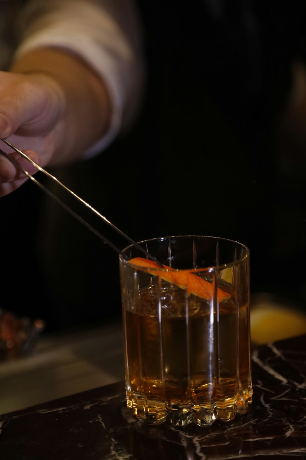 a person cutting an orange into a glass