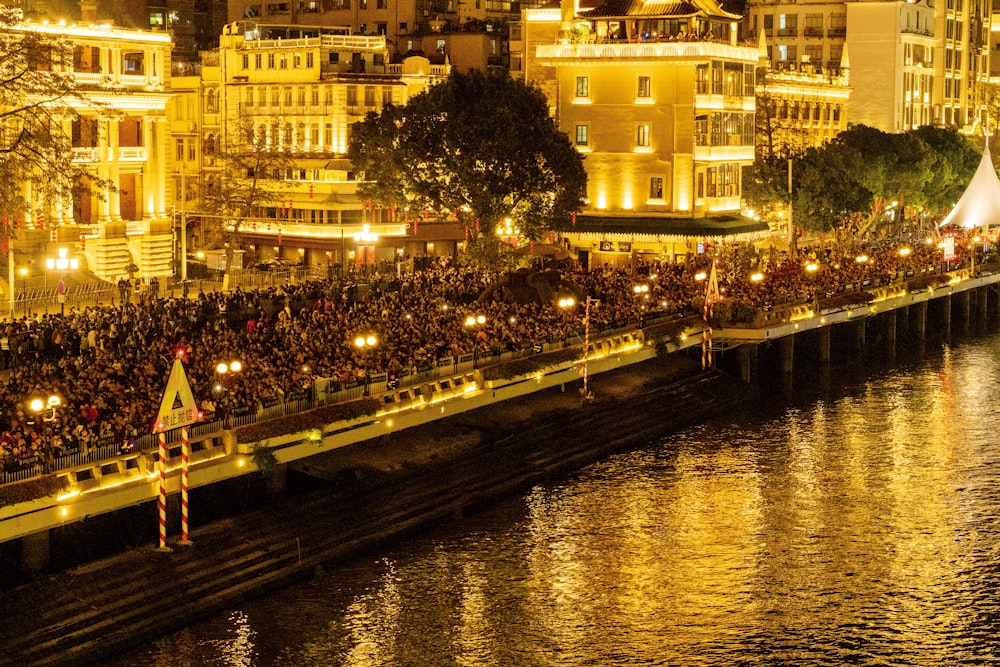 a crowd of people standing on the side of a river