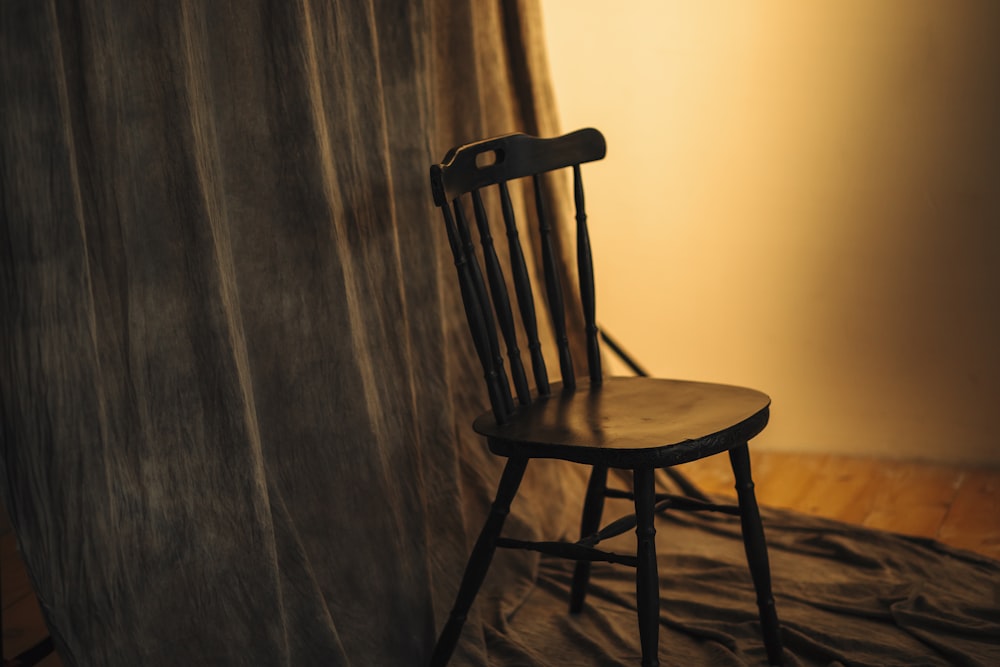 a wooden chair sitting in front of a curtain