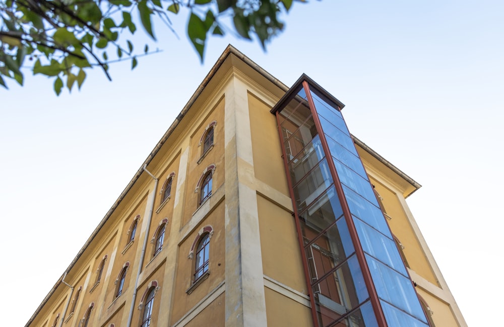 a tall yellow building with a glass window