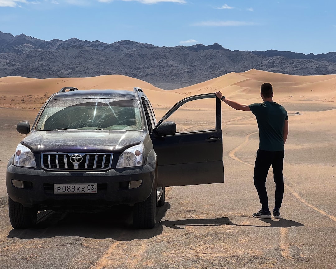 a man standing next to a car in the desert,