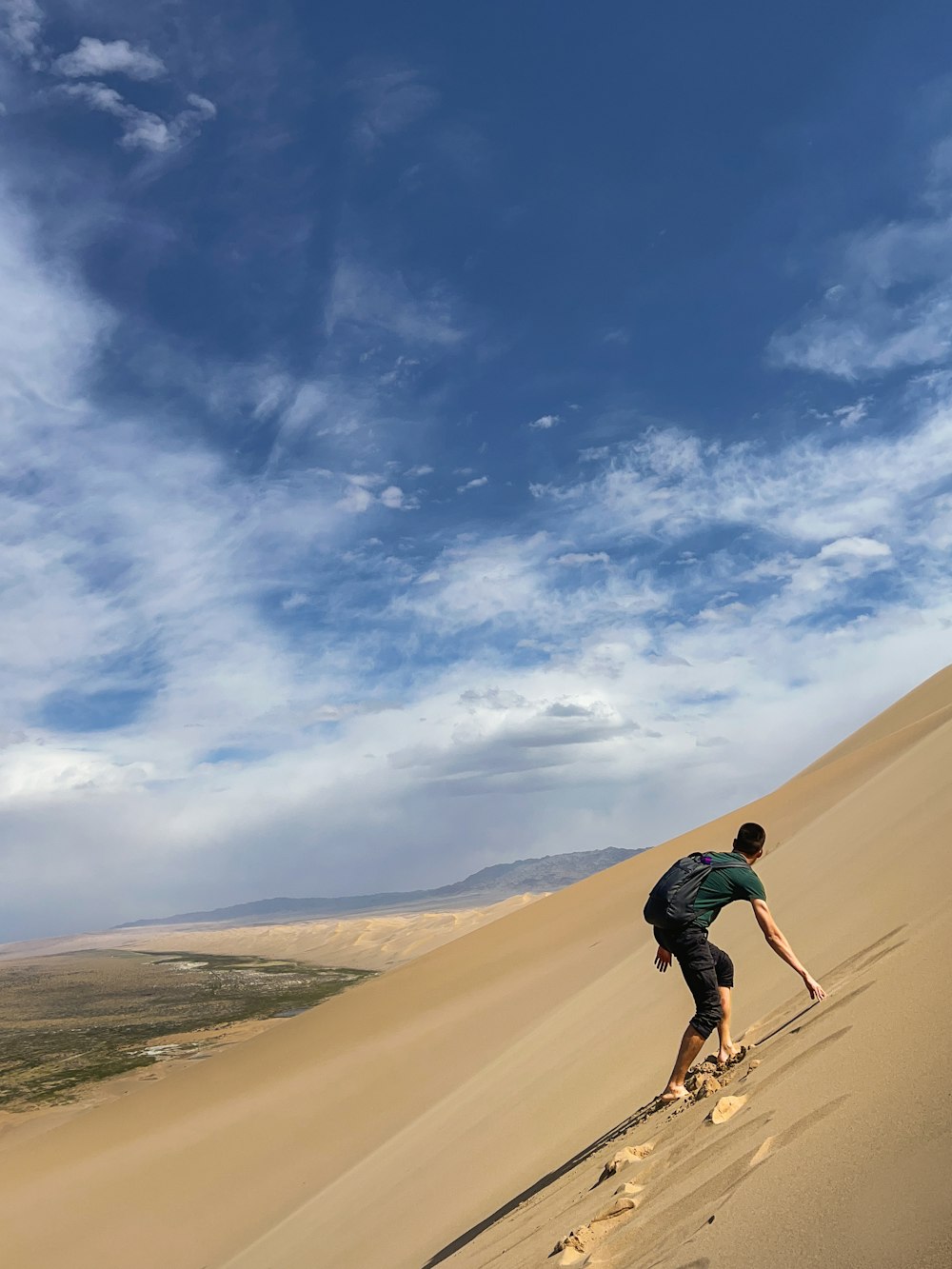 Un hombre montando esquís por la ladera de una duna de arena