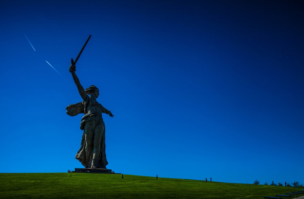 a statue of a woman holding a sword on top of a hill
