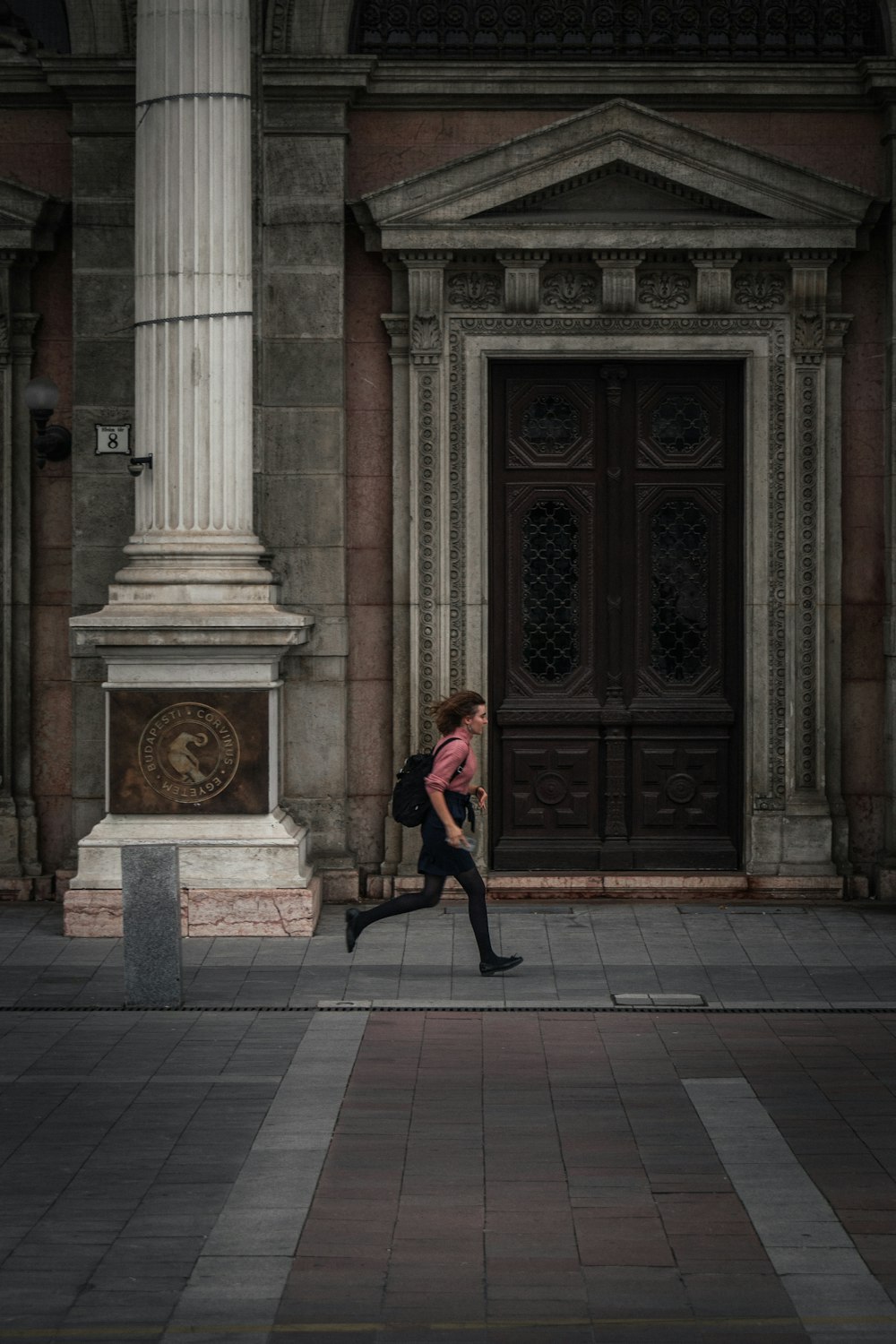 a woman in a pink shirt is walking by a building