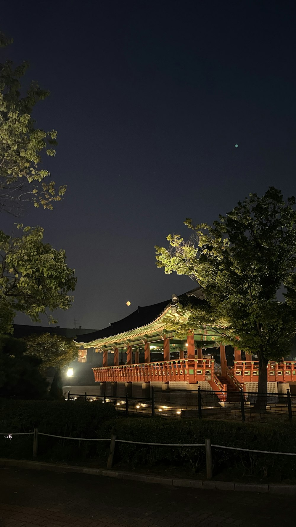Un edificio illuminato di notte con alberi in primo piano