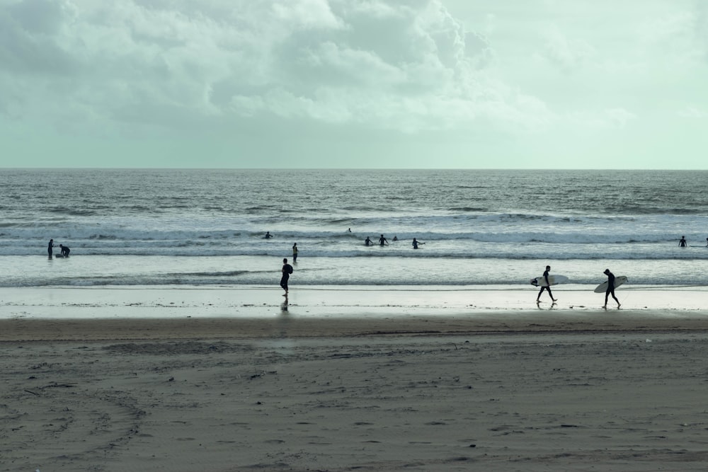 a group of people walking along a beach next to the ocean