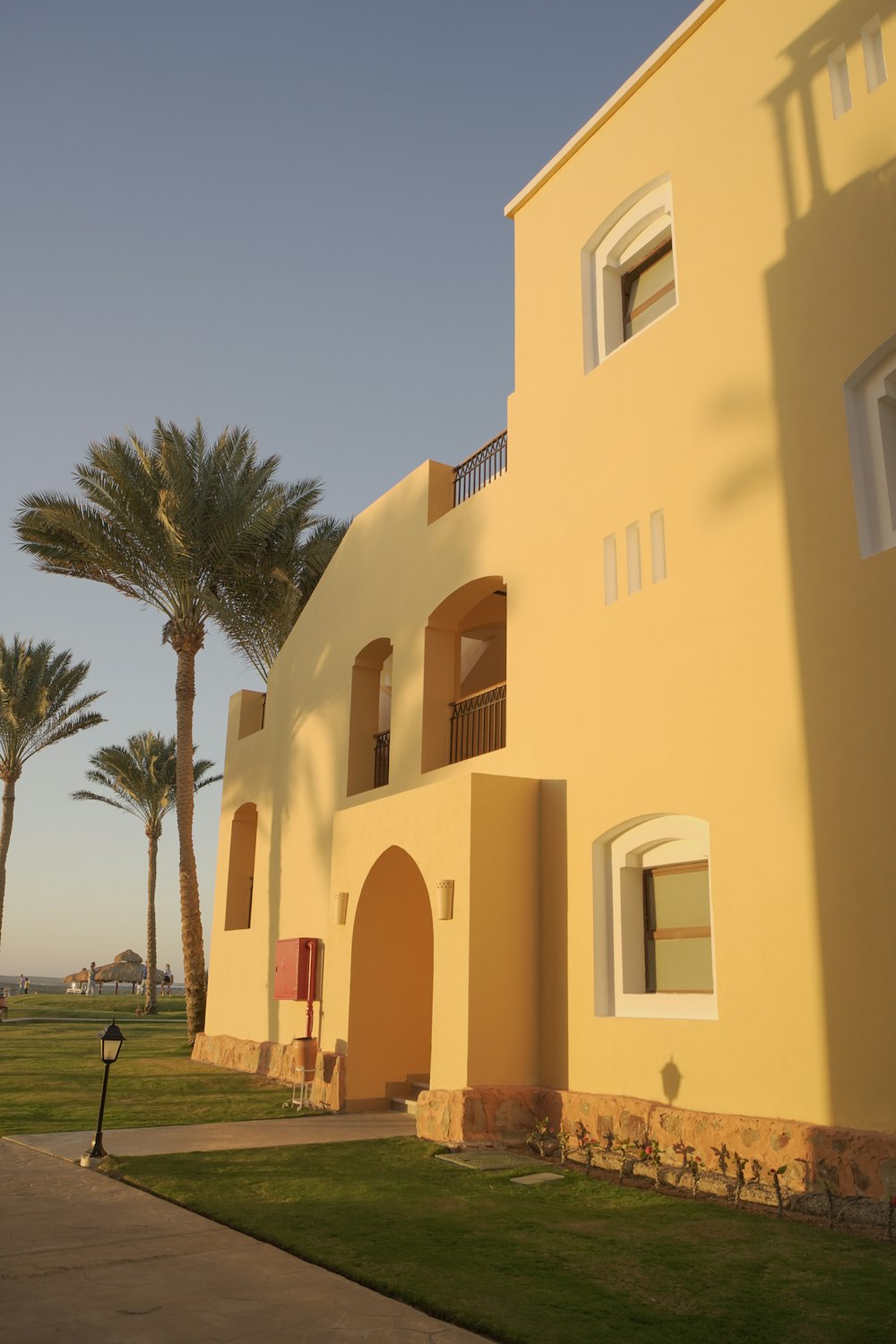 a yellow building with palm trees in the background