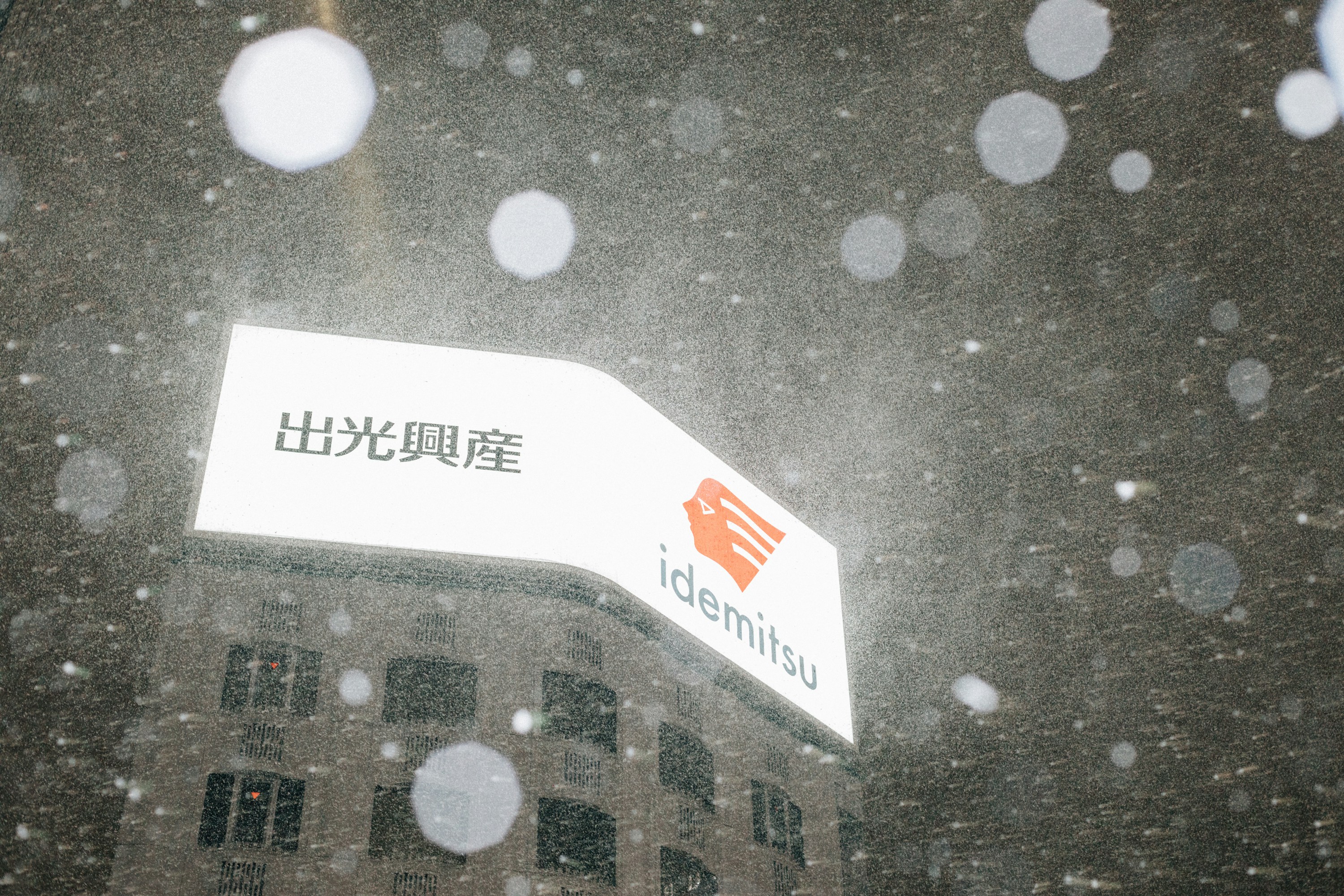 Hand holding a Japanese Kairo heat pack, with snow-covered window in background