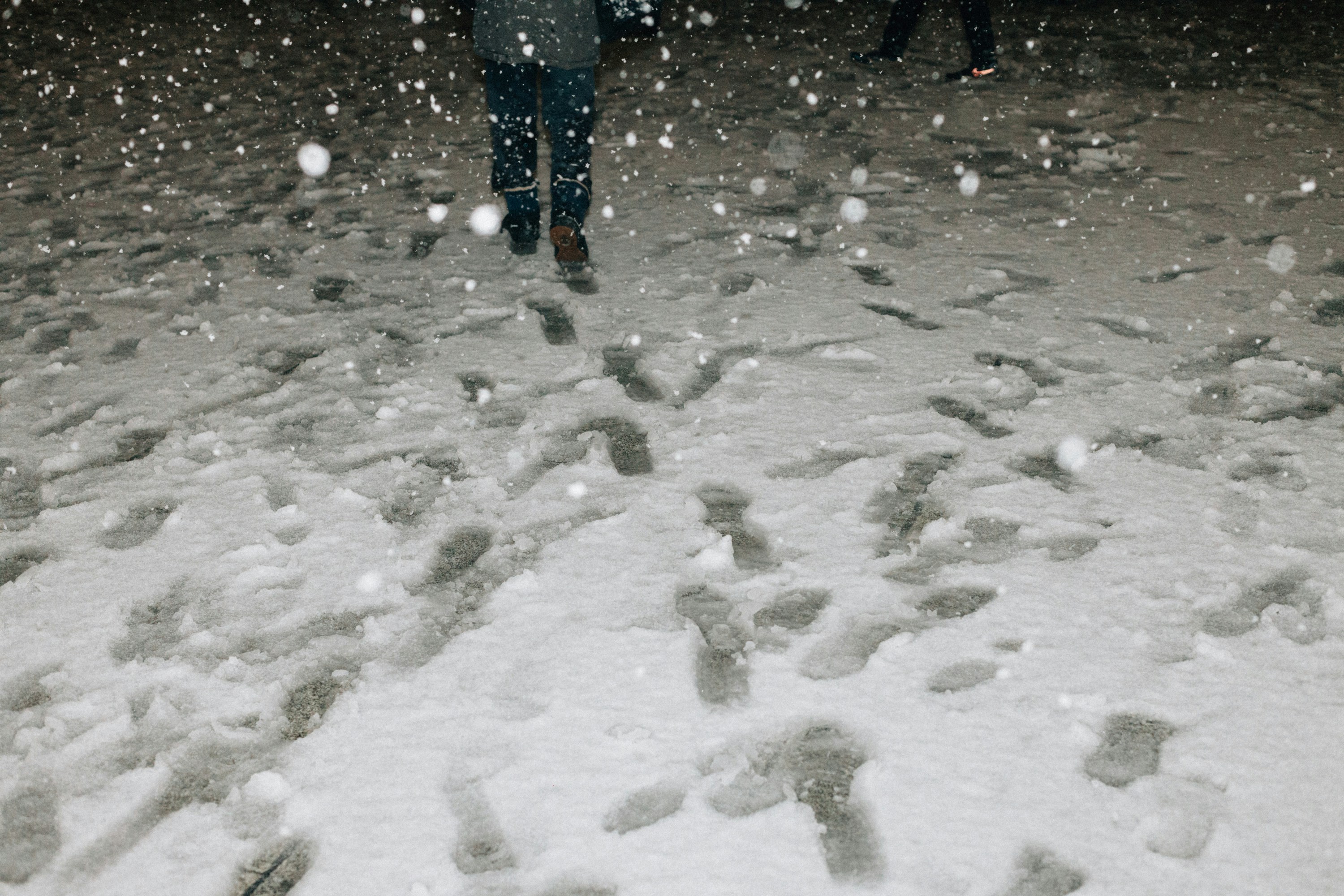 Close-up of a person's feet in winter boots with good grip walking on a snow-covered path