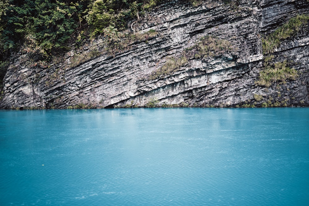 a body of water with a cliff in the background