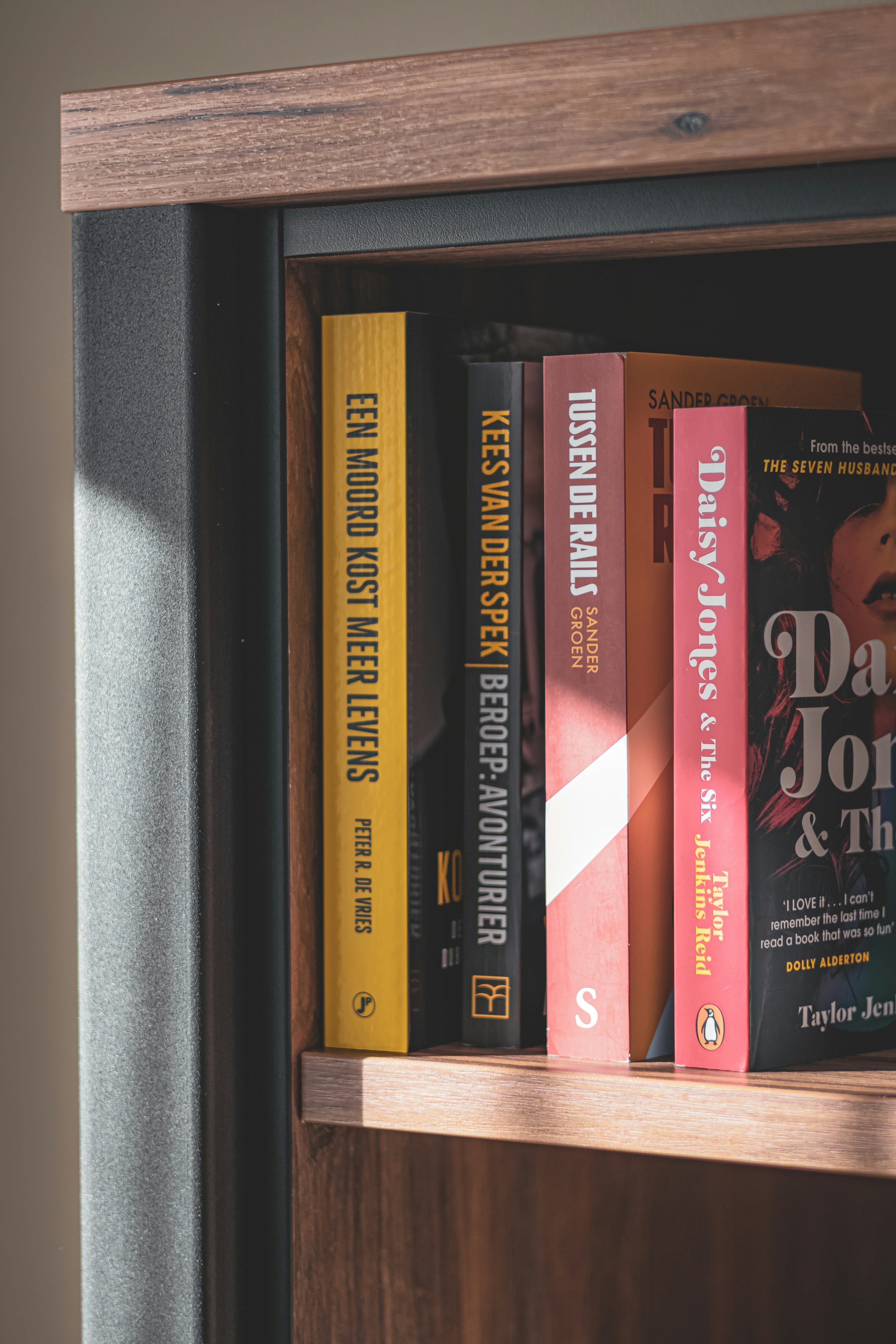 Stack of books with colourful spines on wooden shelf, warm ambient library lighting