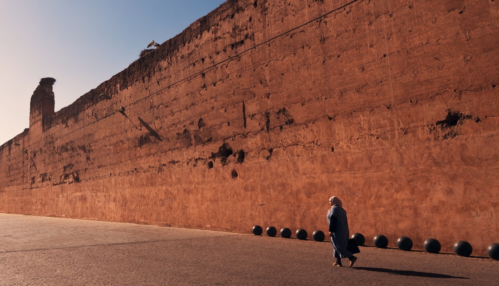 a person walking down a street next to a wall