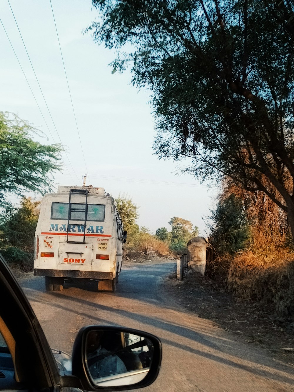 a bus driving down a dirt road next to a forest