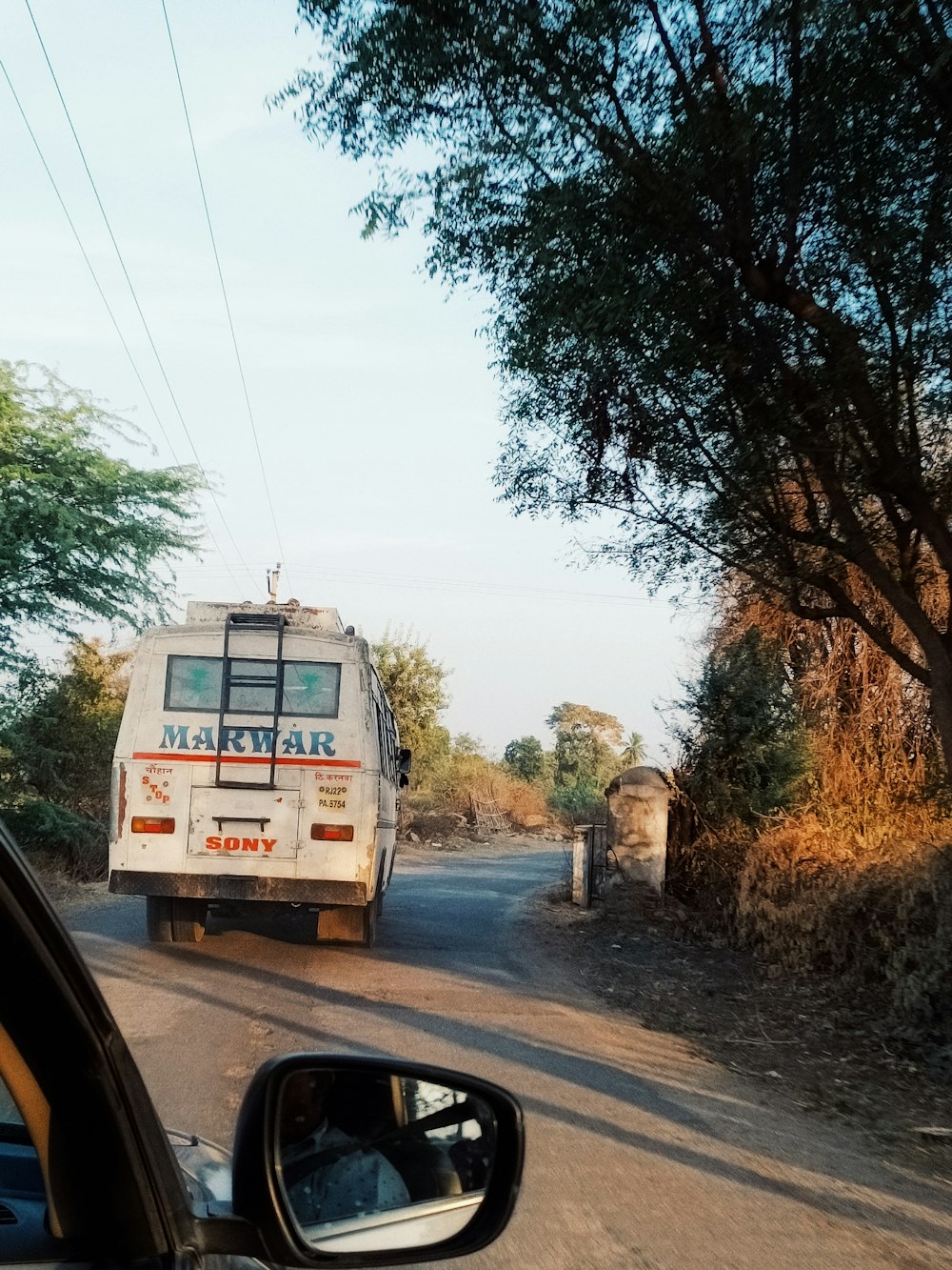 Un autobús que circula por un camino de tierra junto a un bosque