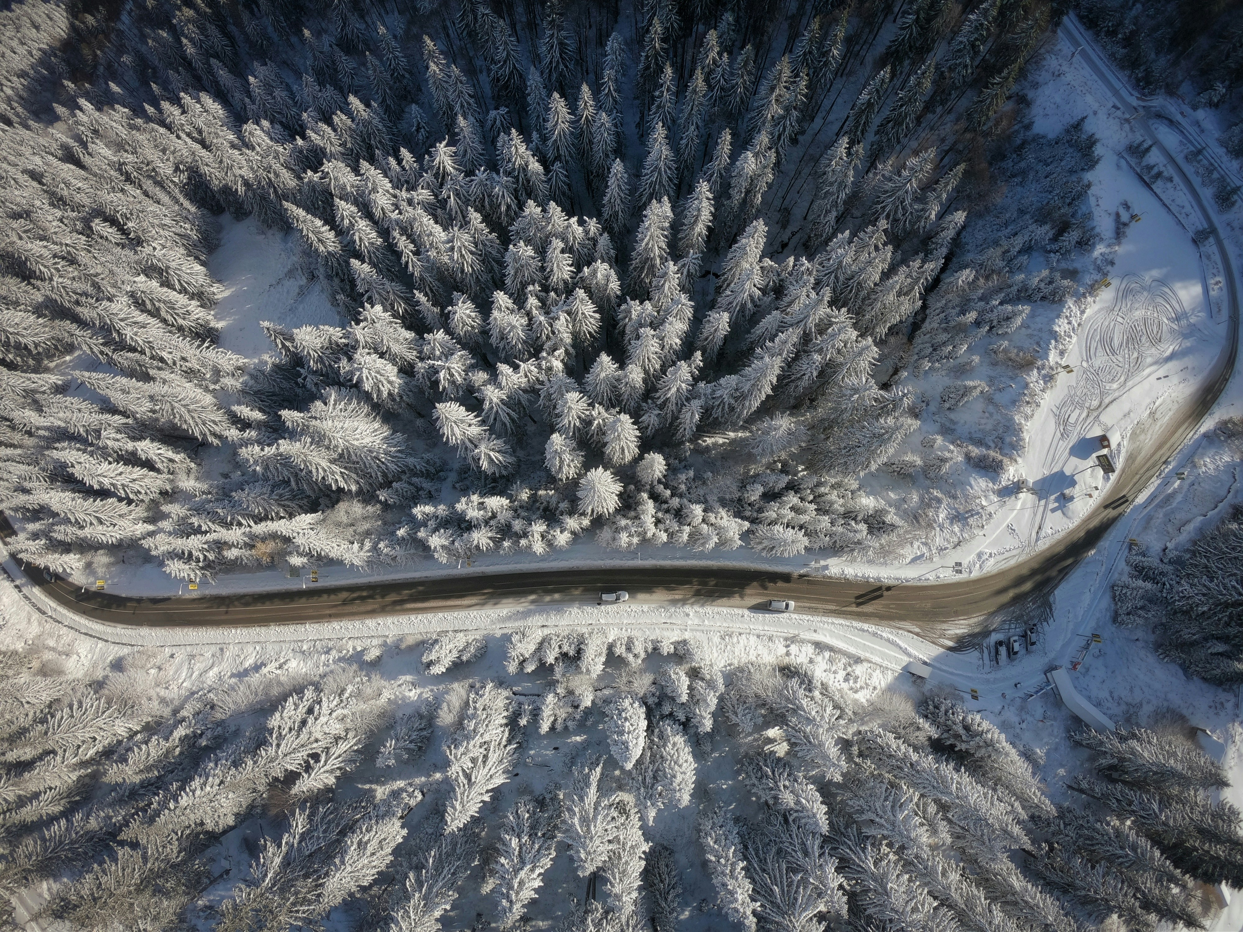 an aerial view of a road surrounded by snow covered trees