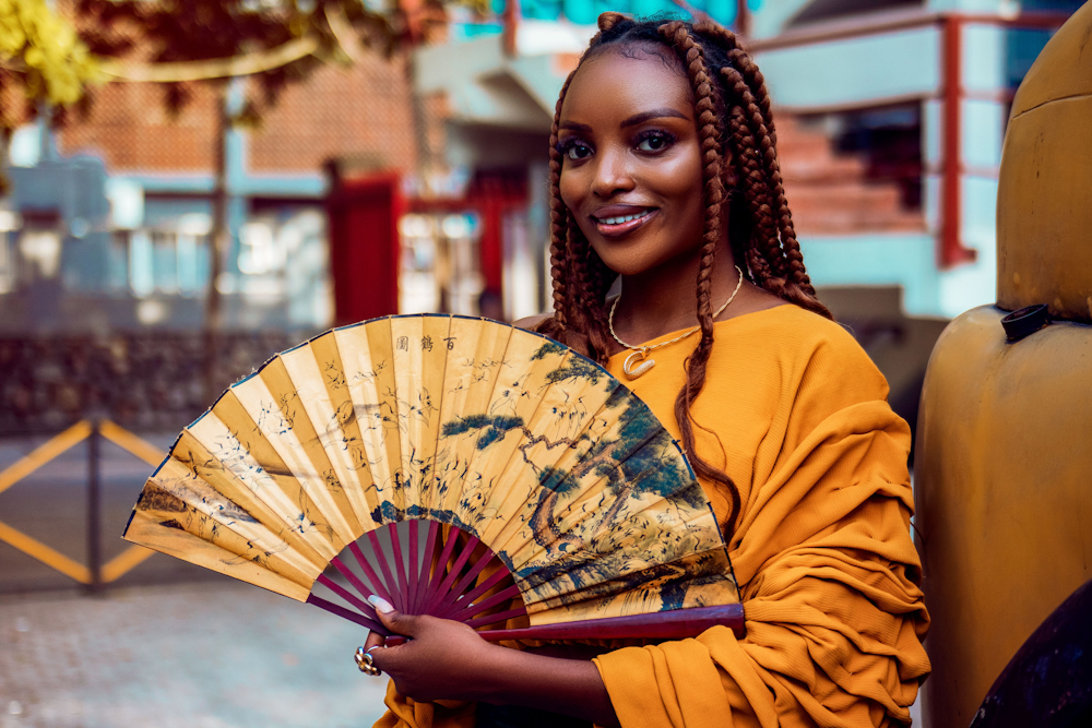 a woman in a yellow dress holding a fan