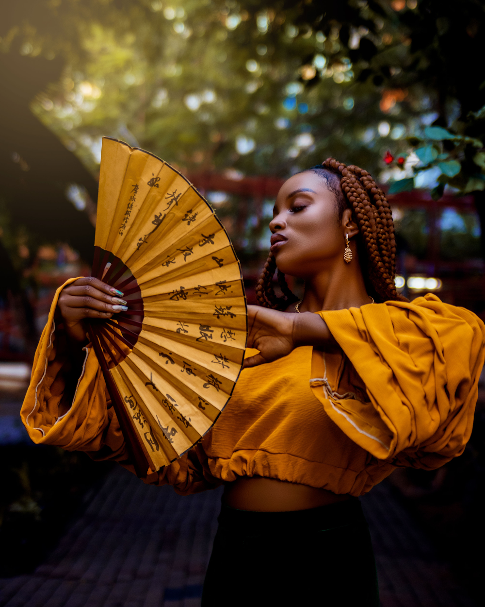 a woman in a yellow top holding a yellow fan