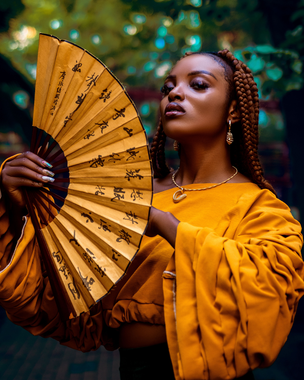 a woman with braids holding a yellow fan