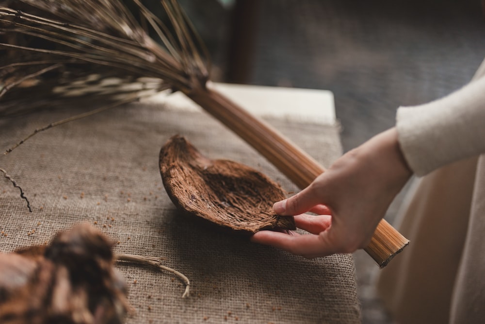 a person holding a wooden spoon over a piece of wood