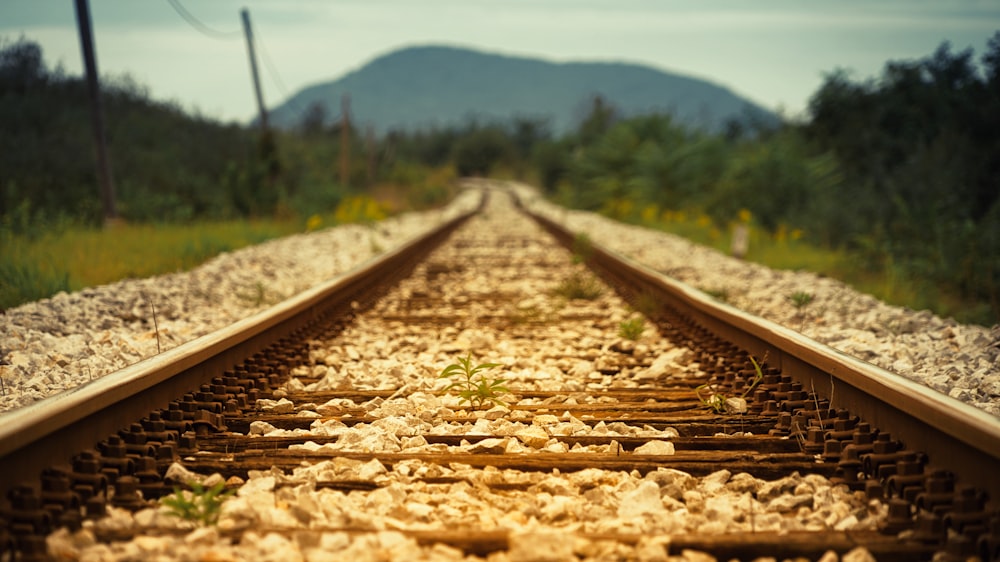 um trilho de trem com uma montanha ao fundo