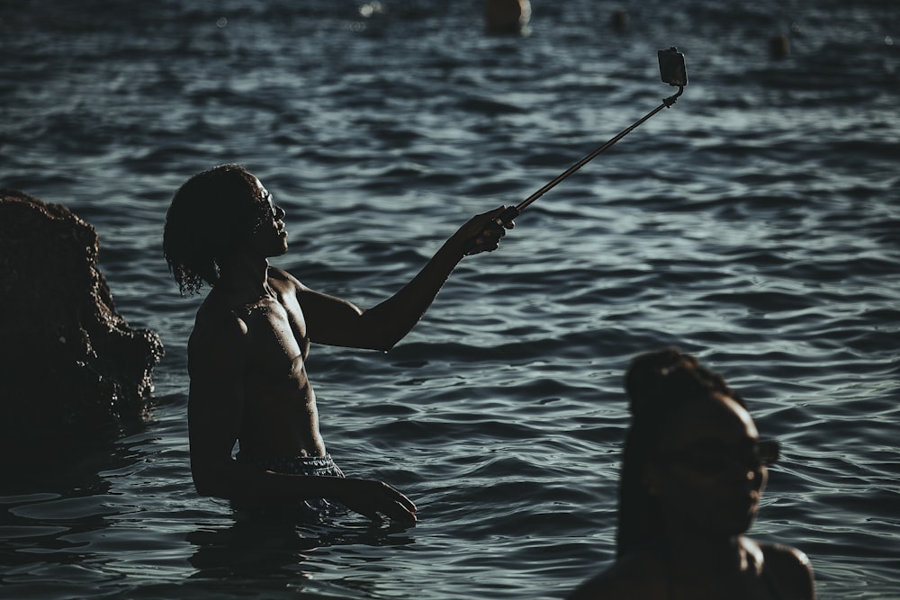 a man standing in a body of water holding a paddle