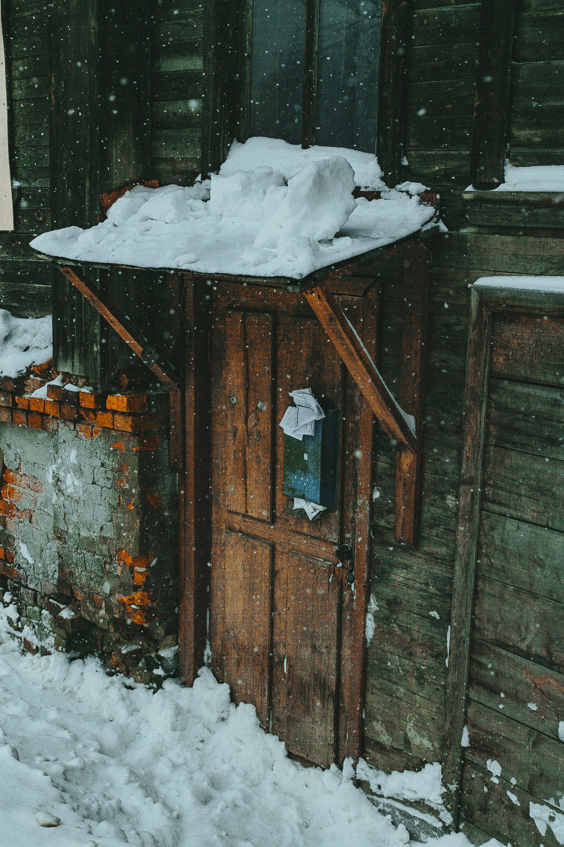 Un edificio de madera cubierto de nieve junto a un edificio