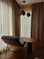 a room with a table, chair and two lamps