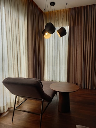 a room with a table, chair and two lamps