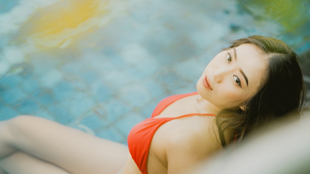 a woman in a red dress sitting next to a pool