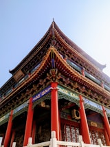 a tall building with red pillars and a blue sky in the background