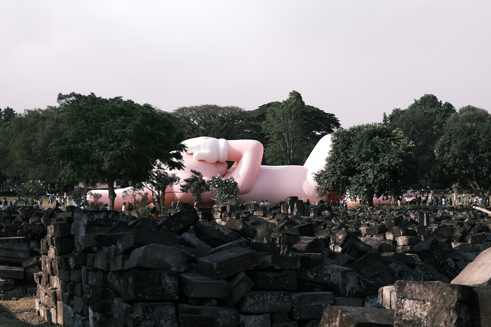 a large pink inflatable animal laying on top of a pile of black rocks