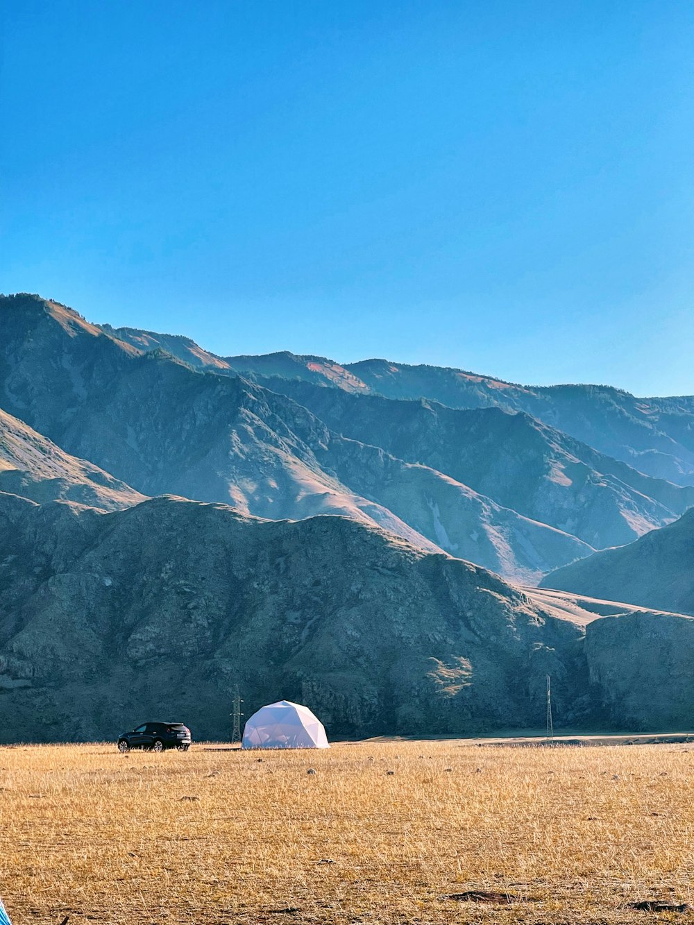 a couple of tents in a field with mountains in the background