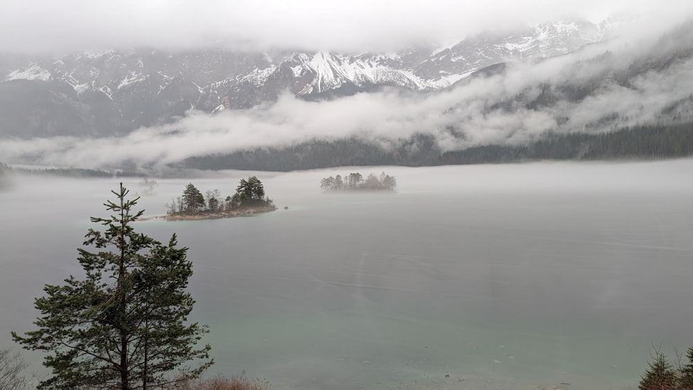 a lake surrounded by mountains covered in fog