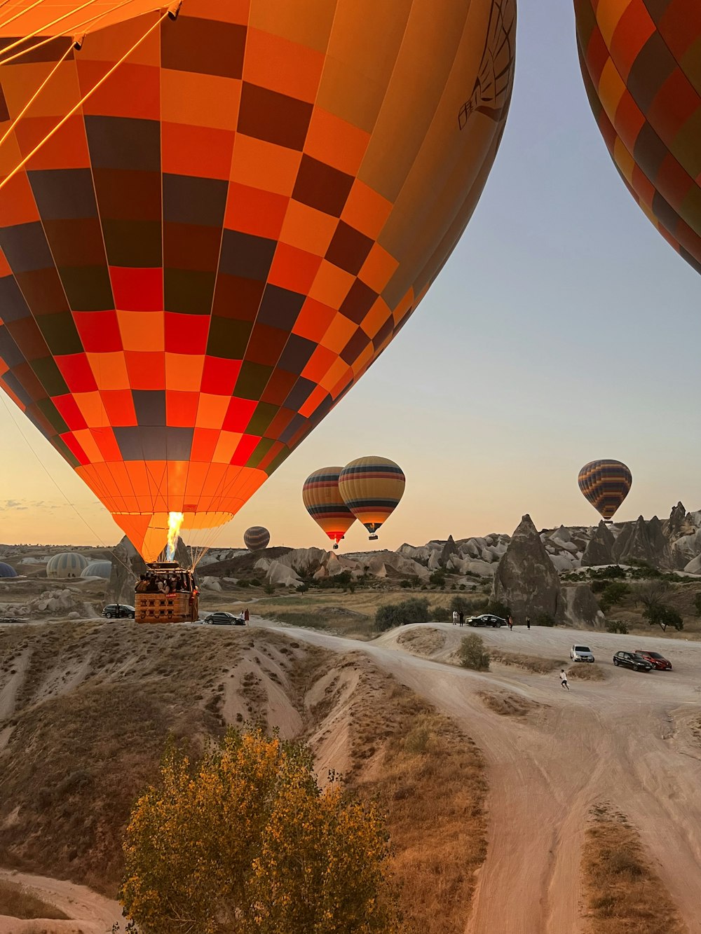 a group of hot air balloons flying over a dirt road