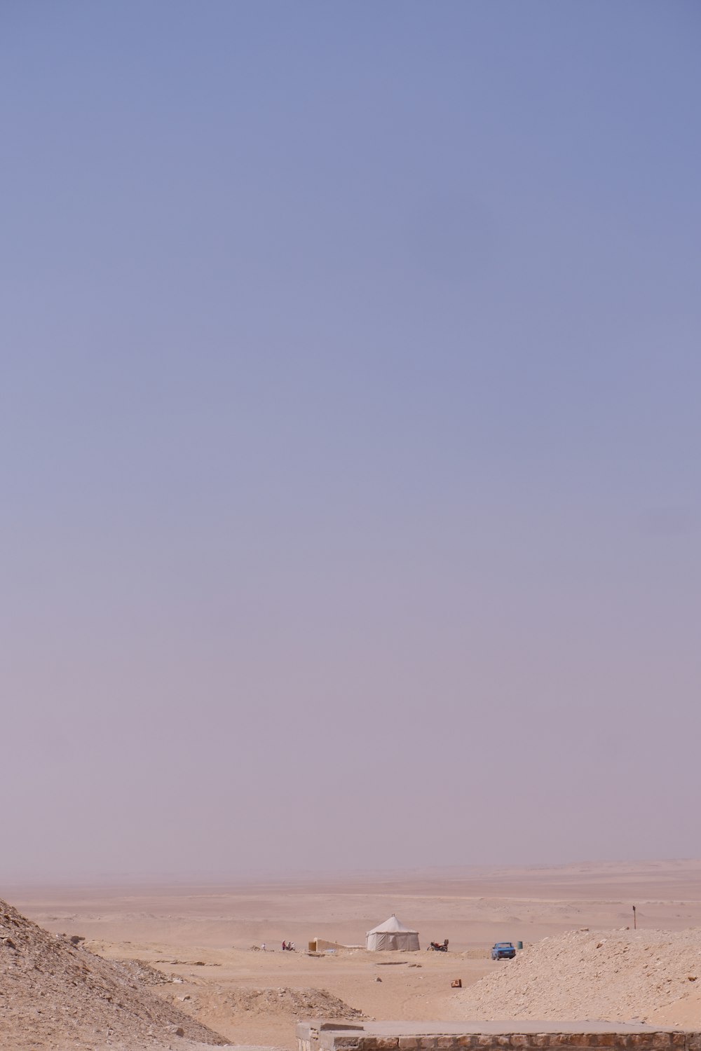 a desert scene with a few vehicles in the distance