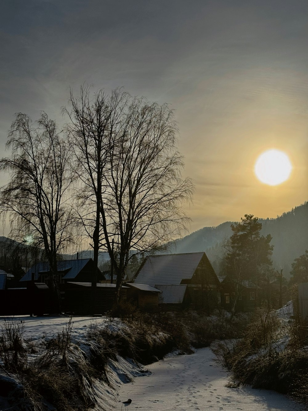 the sun is setting over a small village