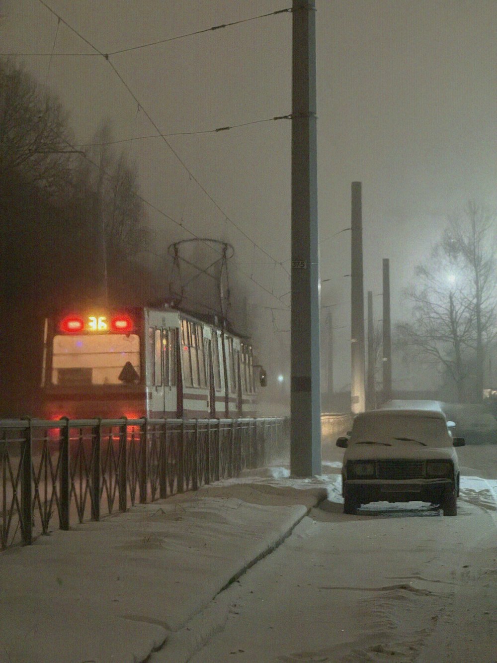 a train traveling down tracks next to a snow covered street