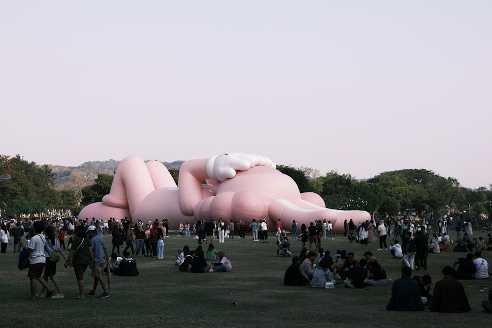 a group of people standing around a giant pink object