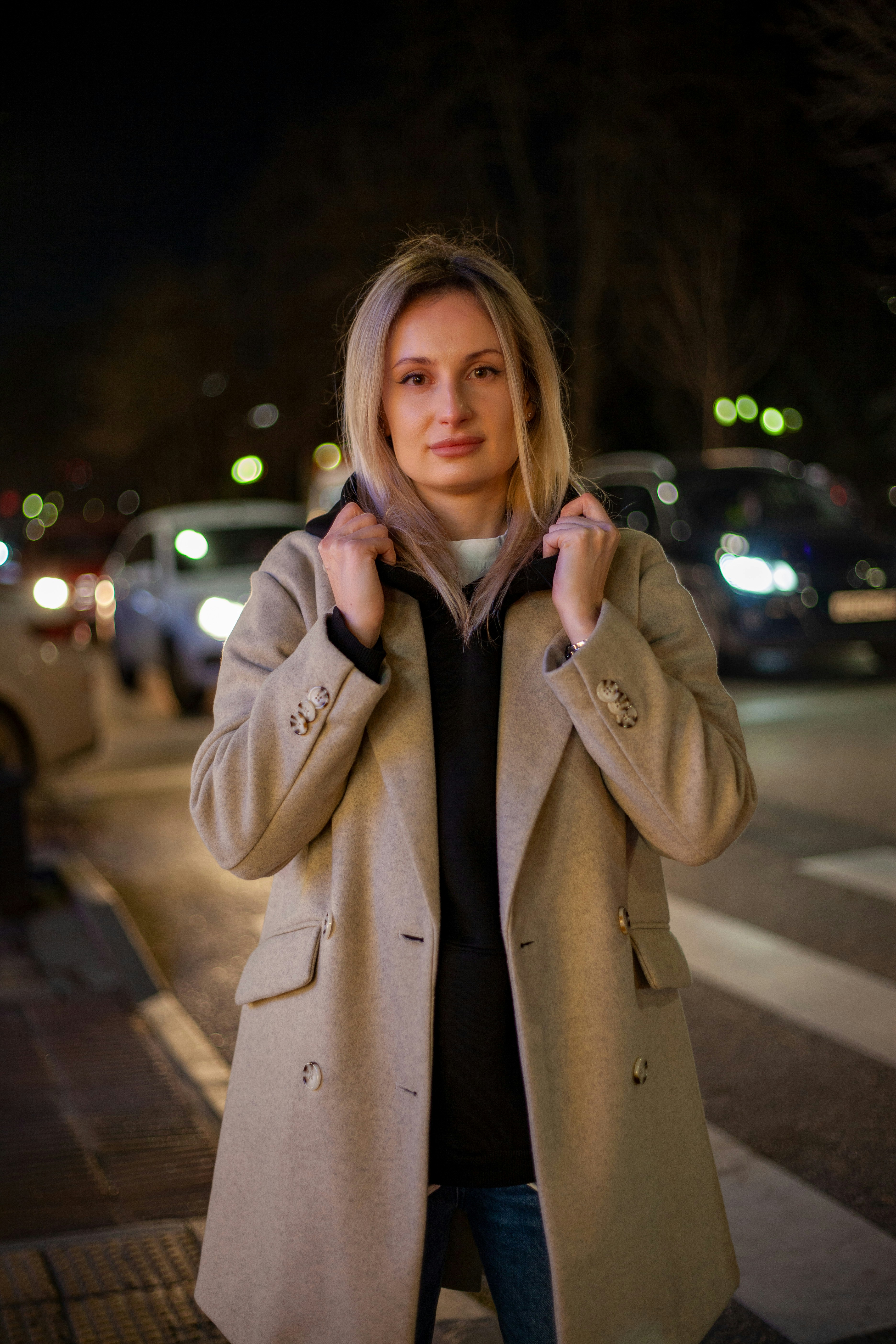 a woman in a coat is standing on the street