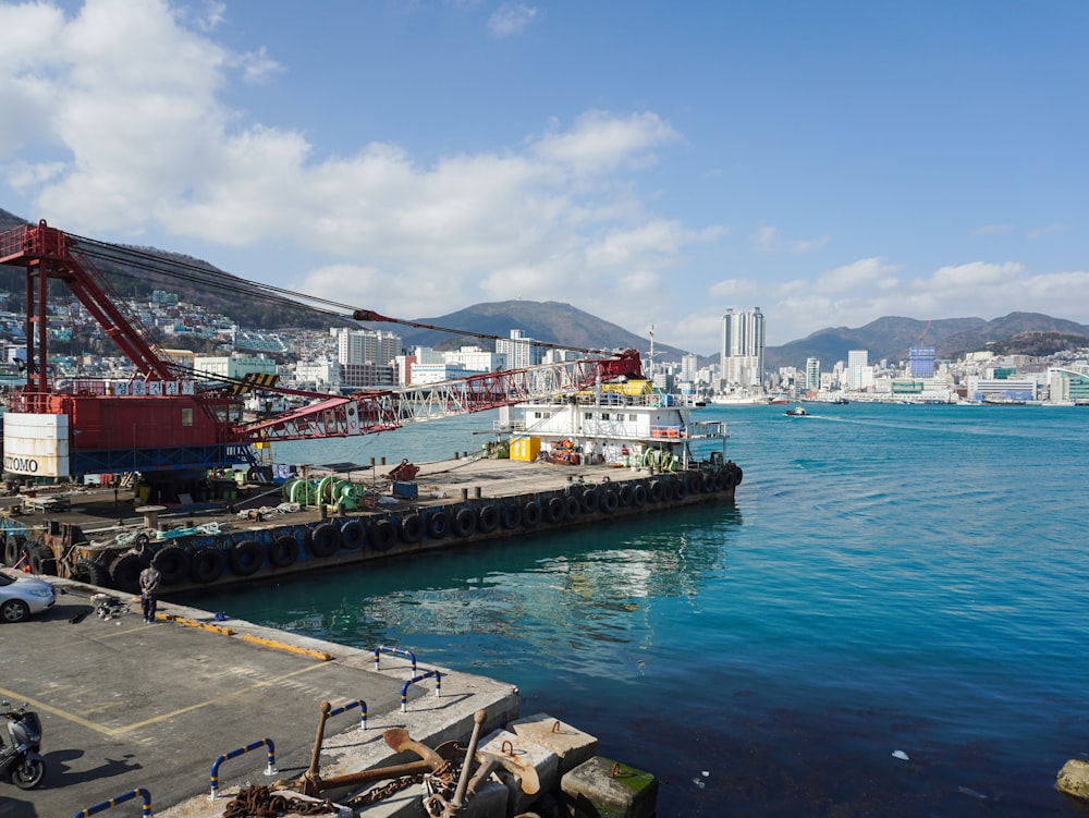 a boat docked at a dock with a city in the background