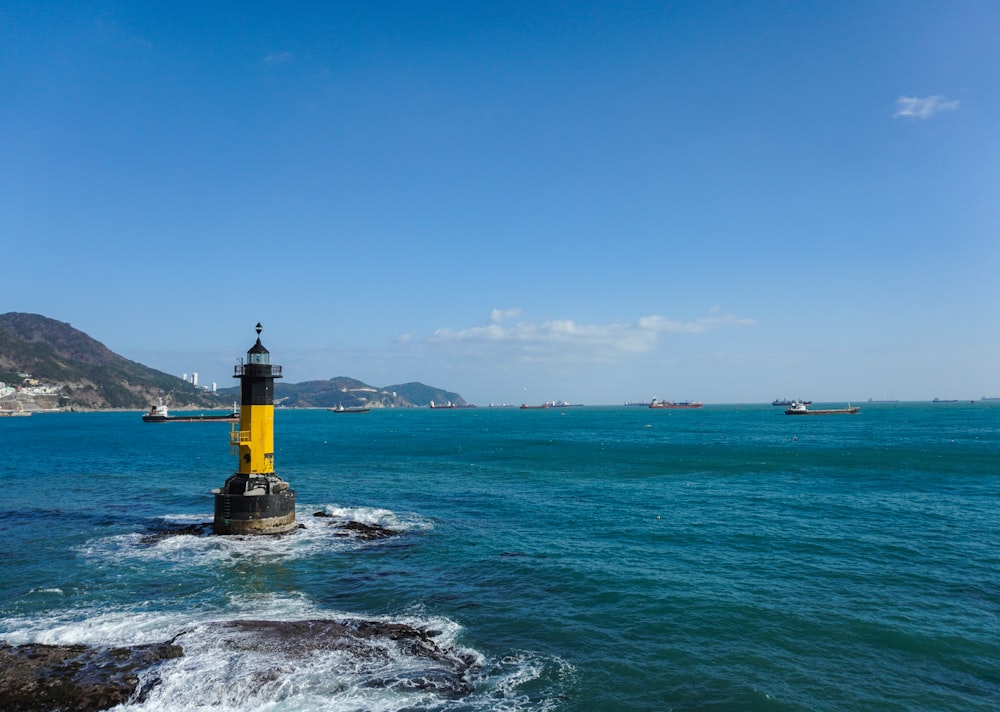 a yellow and black light house in the middle of the ocean