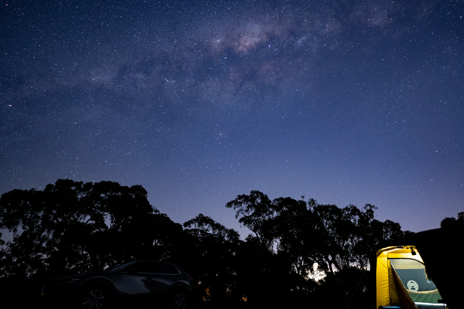 An overlanding vehicle parked beneath a sky crowded with stars
