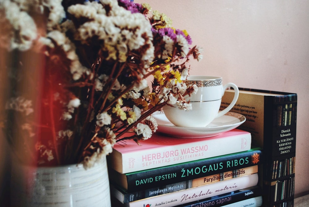 a stack of books sitting next to a vase filled with flowers